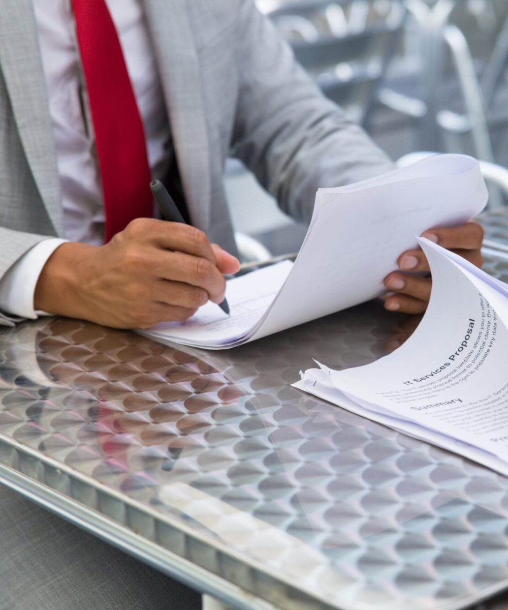 Business partners checking and signing document Business partners checking and signing documents in street cafe. Closeup of papers and writing business man hand. Deal or paperwork concept